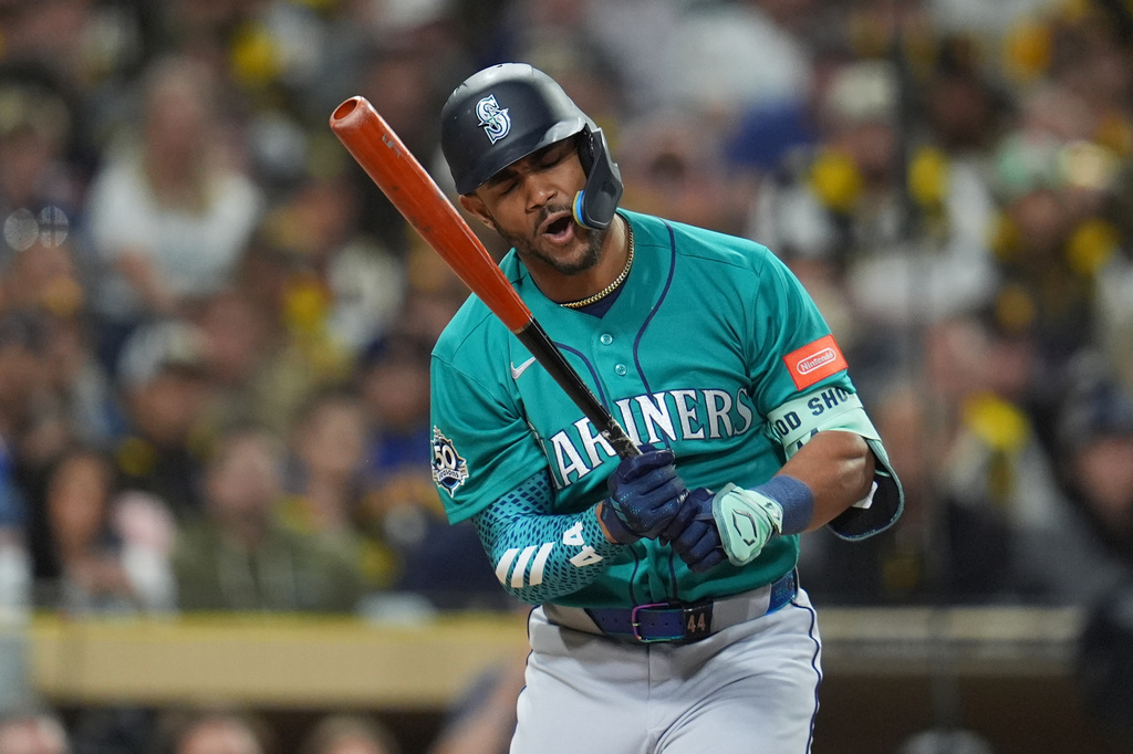 Mariners batter mid-swing in teal uniform with orange bat during a baseball game, crowd in background