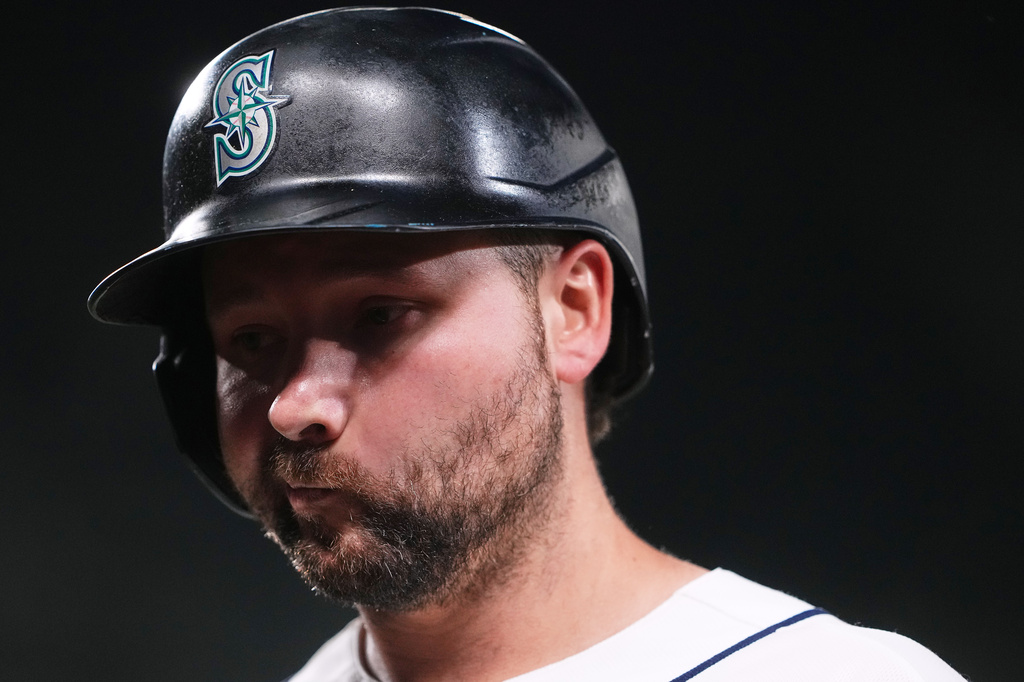 Baseball player wearing a dark helmet with the Seattle Mariners logo, looking down with a beard.