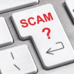 Key on a keyboard labeled SCAM with a red question mark, suggesting online scams or fraud awareness