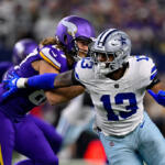 Dallas Cowboys player in white (#13) being tackled by a Minnesota Vikings defender in purple during an NFL game on the field.