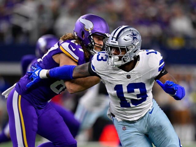 Dallas Cowboys player in white (#13) being tackled by a Minnesota Vikings defender in purple during an NFL game on the field.