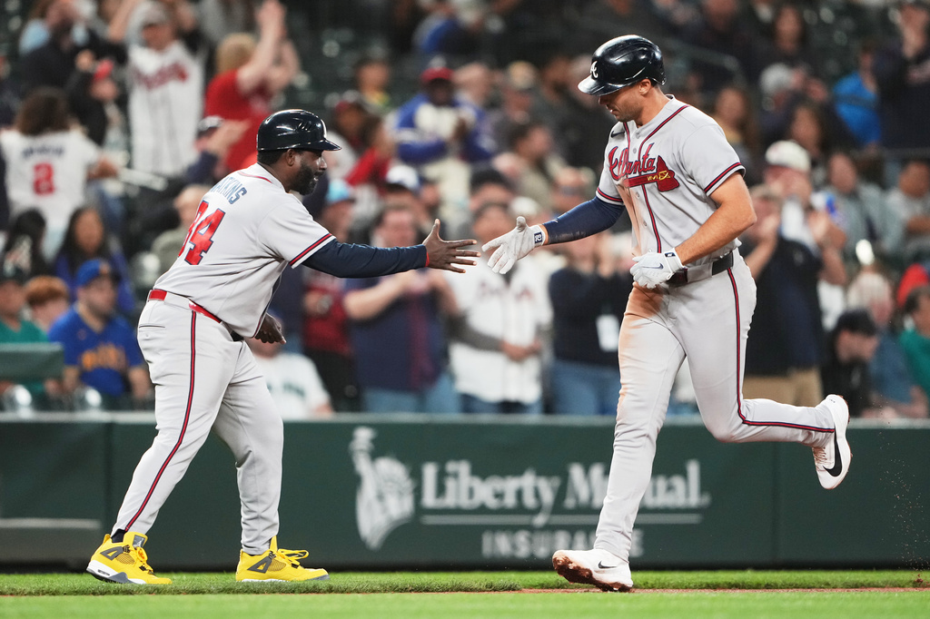 Two Braves players exchange a high-five on the baseball field as a crowd cheers in the background.