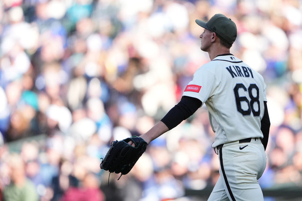 Baseball pitcher with jersey reading 'KIRBY' and number 68 adjusts his glove during a game, crowd in the stands blurred behind him.