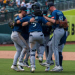 A group of baseball players in blue uniforms huddle together on the field in celebration.