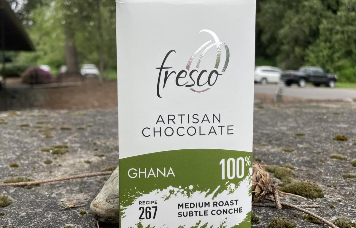 Close-up of a Fresco artisan chocolate box showing Ghana 100% with green accent at the bottom outside on the ground.