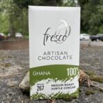 Close-up of a Fresco artisan chocolate box showing Ghana 100% with green accent at the bottom outside on the ground.