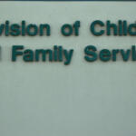 Teal raised lettering reading 'Division of Children and Family Services' on a pale wall.