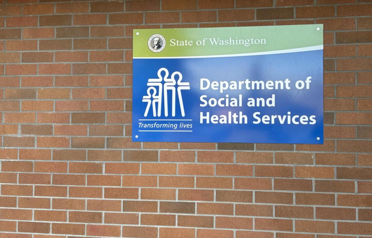 Blue and green Department of Social and Health Services sign mounted on a brick wall in Washington state.