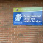Blue and green Department of Social and Health Services sign mounted on a brick wall in Washington state.
