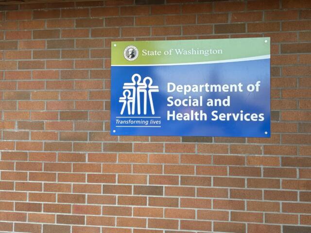Blue and green Department of Social and Health Services sign mounted on a brick wall in Washington state.