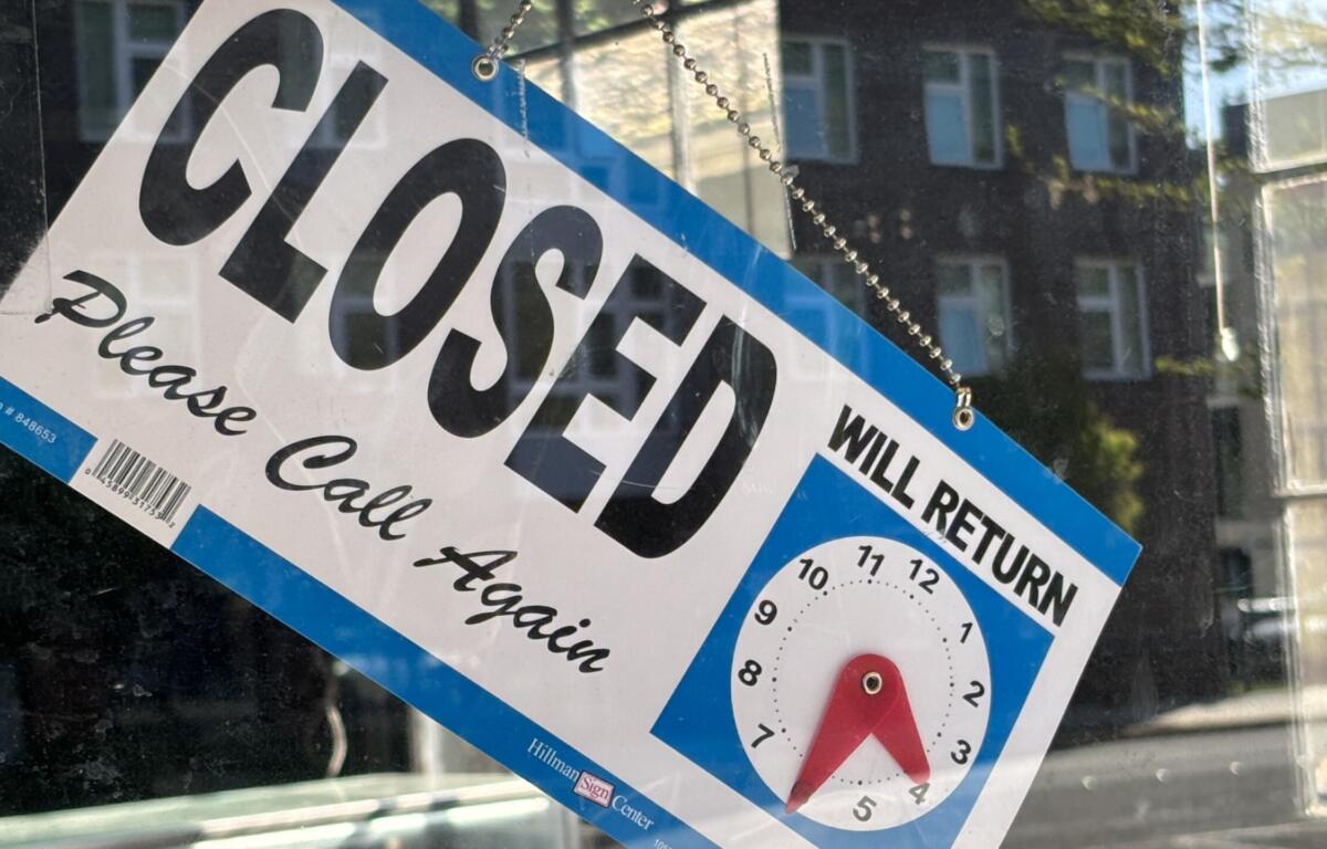Storefront window displaying a large 'CLOSED' notice with 'Will return' text and a clock illustration showing return hours.