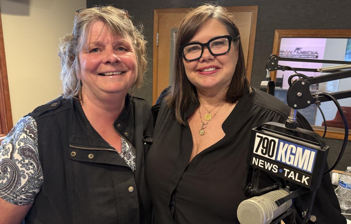 Two women posing for a selfie in a radio studio, smiling, with microphones and a 790 KGM News Talk sign visible in the foreground behind them.
