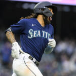 Seattle Mariners player in blue uniform running the bases, wearing a batting helmet and white gloves during a game