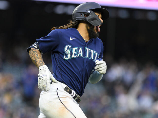 Seattle Mariners player in blue uniform running the bases, wearing a batting helmet and white gloves during a game