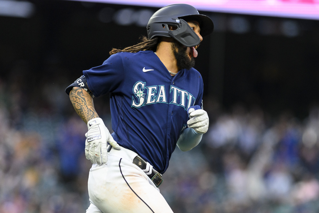 Seattle Mariners player in blue uniform running the bases, wearing a batting helmet and white gloves during a game