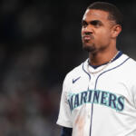Baseball player in Mariners uniform making a pouty, determined expression on the field.