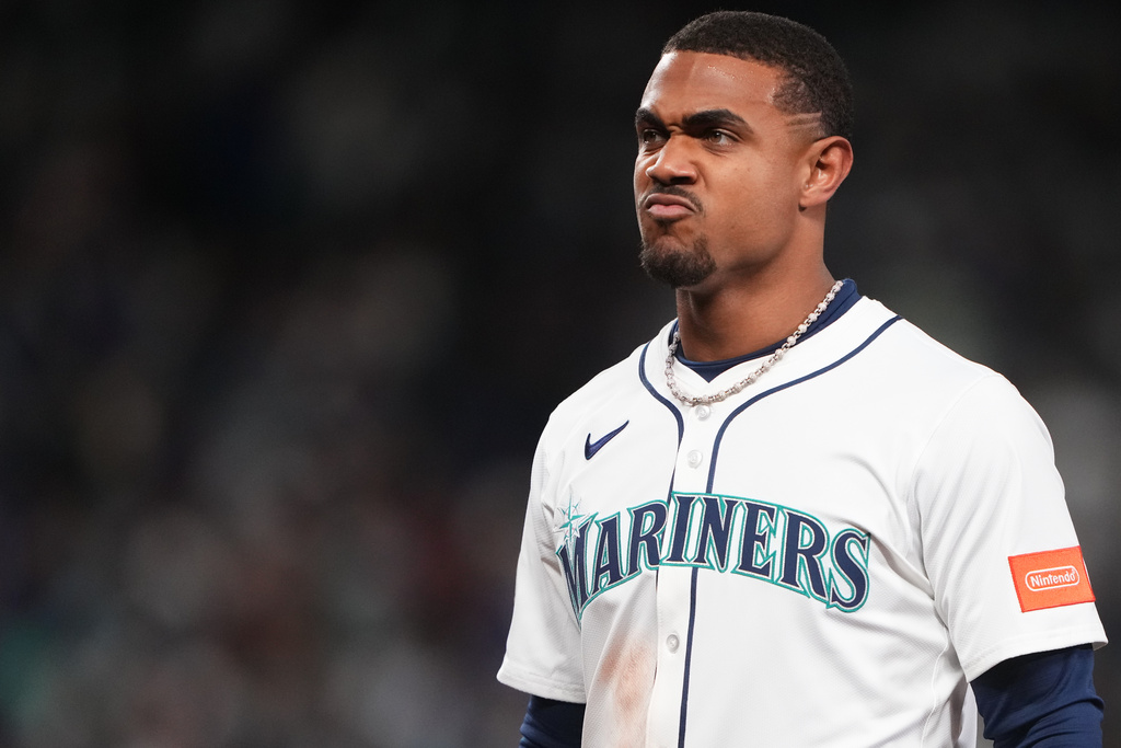 Baseball player in Mariners uniform making a pouty, determined expression on the field.