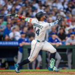 Baseball player Rodriguez, number 14, swings a bat during a game with a packed stadium crowd in the background.