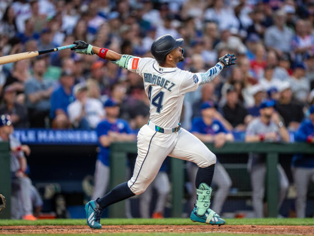 Baseball player Rodriguez, number 14, swings a bat during a game with a packed stadium crowd in the background.