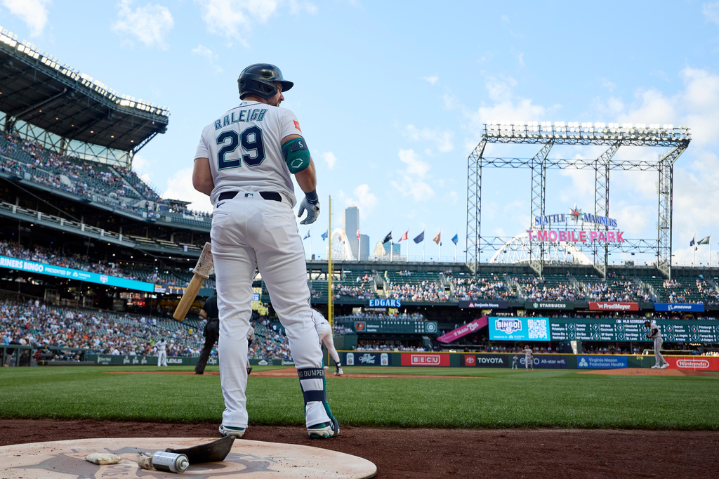 Baseball batter wearing number 29 stands at home plate with bat in hand, seen from behind in a full stadium.