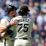 Two baseball players embrace on the field; back of Munoz's jersey shows number 75 as the crowd blurs in the background.