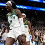 Storm women’s basketball player (#11) shouts in celebration on the court, crowd cheering behind her in the arena.