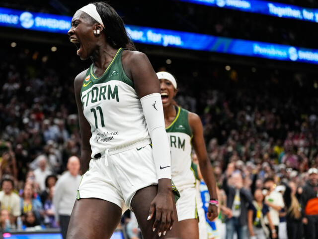 Storm women’s basketball player (#11) shouts in celebration on the court, crowd cheering behind her in the arena.