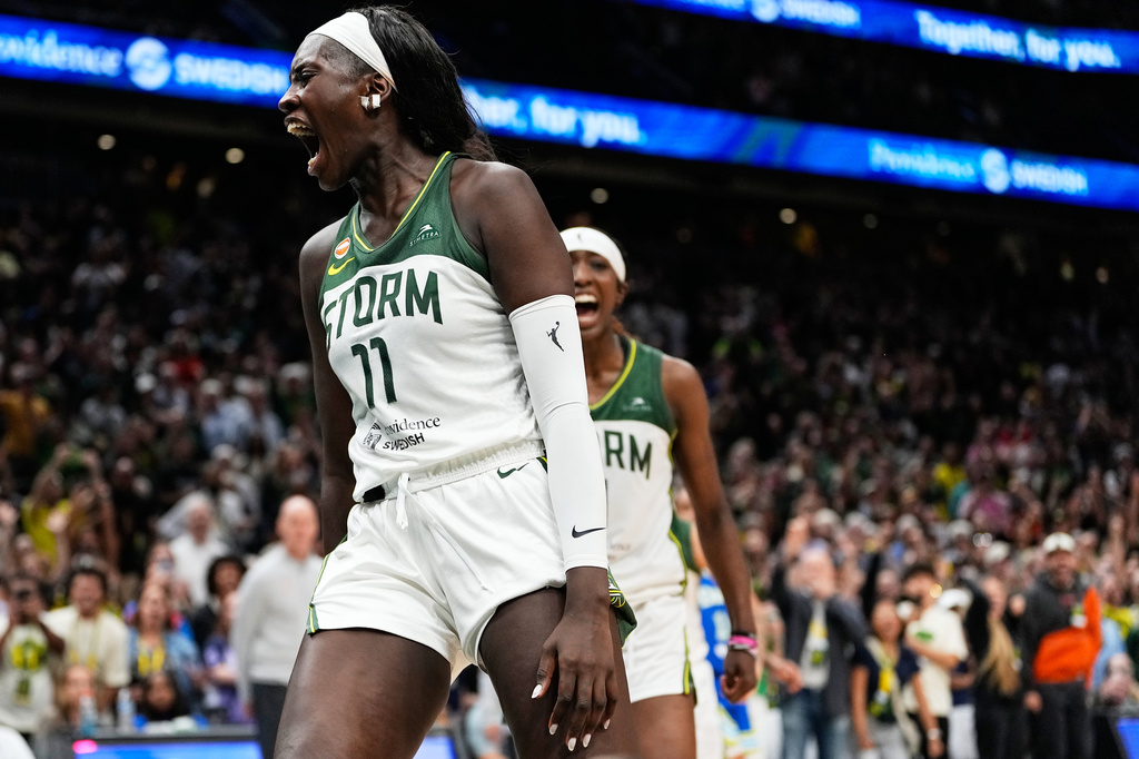 Storm women’s basketball player (#11) shouts in celebration on the court, crowd cheering behind her in the arena.