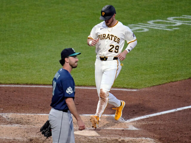 Pittsburgh Pirates player in white uniform #29 runs near home plate as an opposing player in blue watches from the infield dirt and grass nearby.