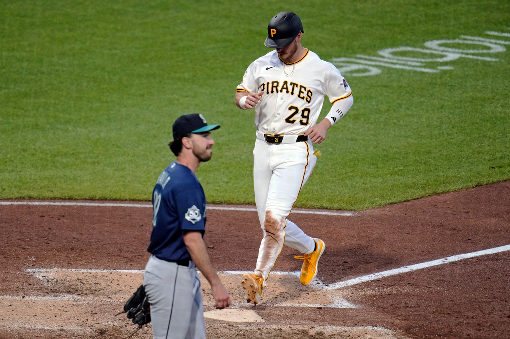 Pittsburgh Pirates player in white uniform #29 runs near home plate as an opposing player in blue watches from the infield dirt and grass nearby.
