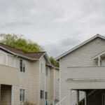 Row of beige two-story townhouses with white trim and balconies under a cloudy sky.