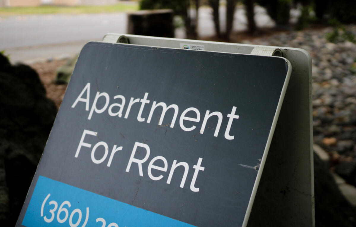Signboard advertising an apartment for rent with a blue price strip in the foreground.