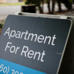Signboard advertising an apartment for rent with a blue price strip in the foreground.