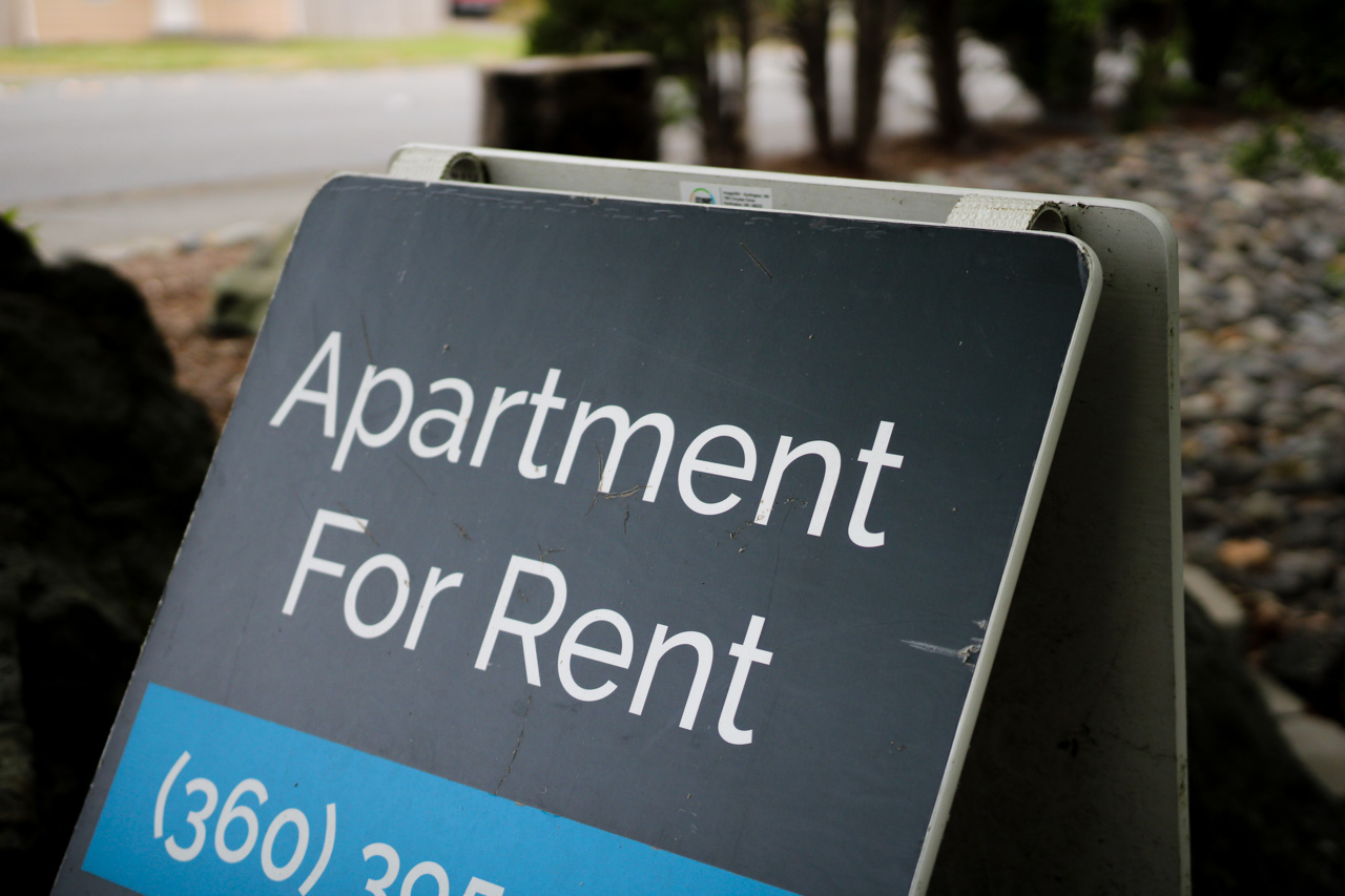 Signboard advertising an apartment for rent with a blue price strip in the foreground.