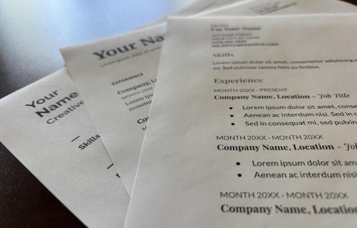 Close-up of printed resumes with placeholder text like 'Your Name', showing sections such as Experience and Skills on white paper.