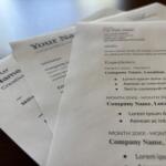 Close-up of printed resumes with placeholder text like 'Your Name', showing sections such as Experience and Skills on white paper.