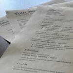 Close-up of multiple resume templates with placeholder text like 'Your Name' and 'Education' on a textured surface.