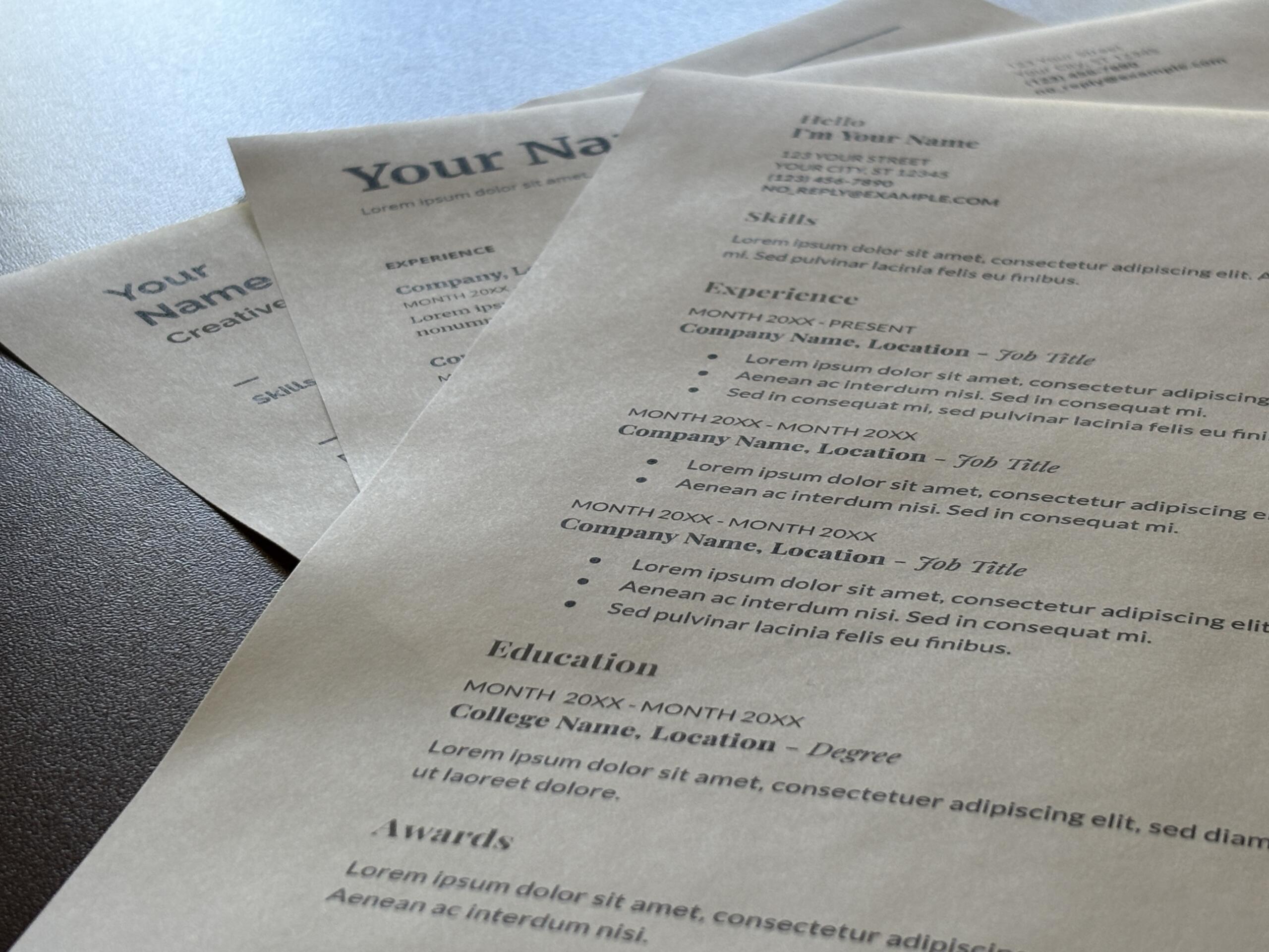 Close-up of multiple resume templates with placeholder text like 'Your Name' and 'Education' on a textured surface.