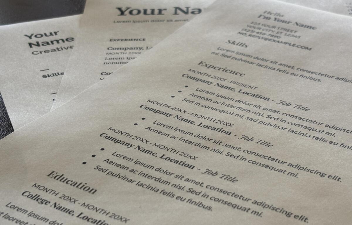 Close-up of overlapping resumes on a desk, showing placeholders like 'Your Name' and headings such as Experience and Skills with lorem ipsum text.