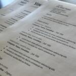 Multiple sheets of resume-style documents overlapped on a desk, with headings like Skills and Experience in lorem ipsum text (informational).