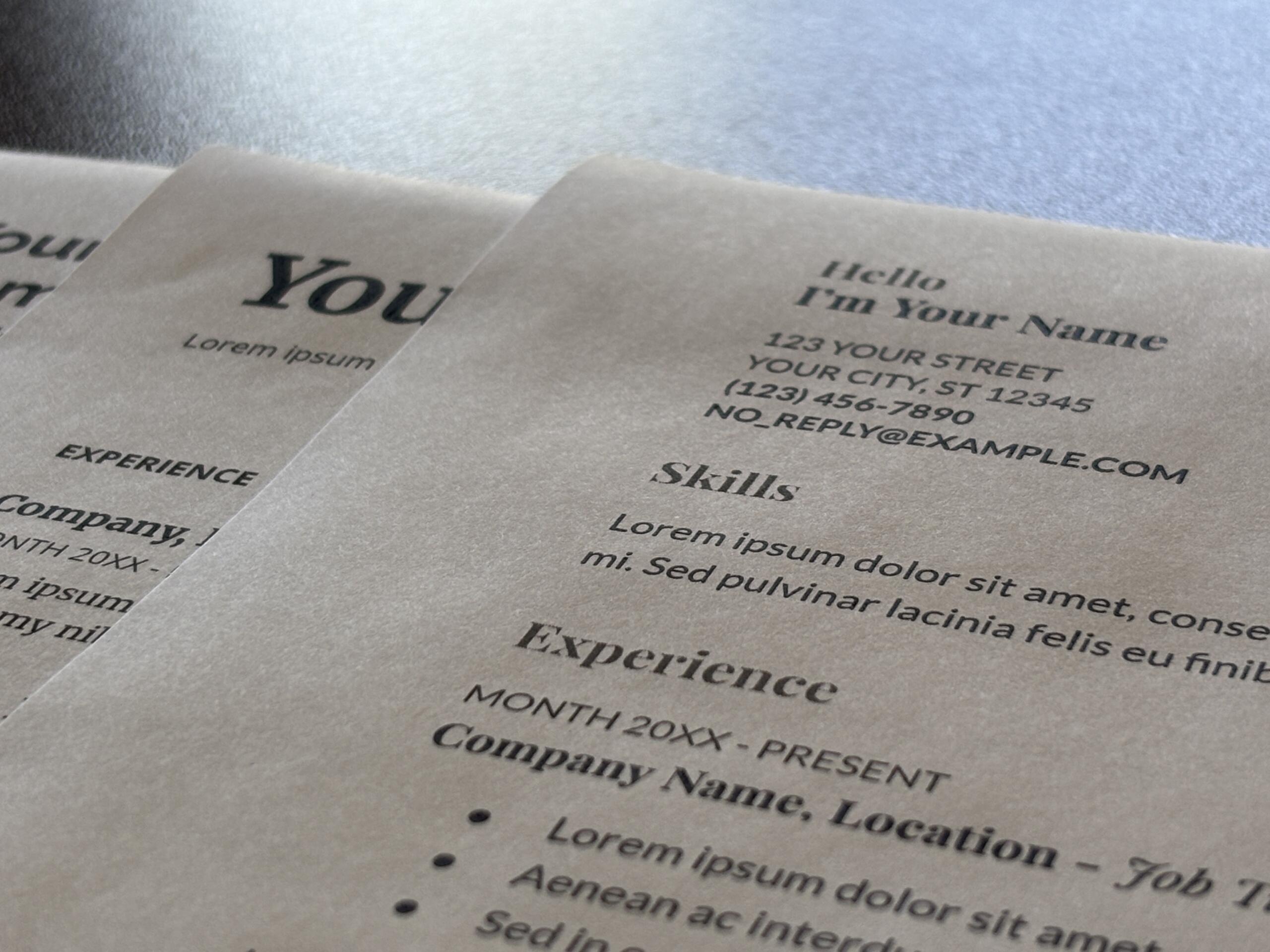 Close-up of printed sheets with placeholder text and headings like 'Hello I'm Your Name' on a light background temporary layout.