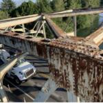 Close-up of rusted steel bridge girders with rivets, overlooking a road with a white truck beneath and trees in the background