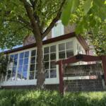 Two-story house with large white-framed windows, shaded by a leafy tree; a weathered sign reads 'Historic Site, The Pickett House'.