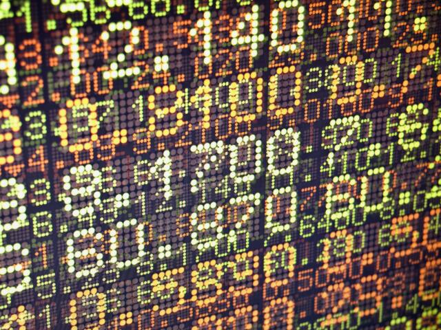 Close-up of a colorful LED dot matrix displaying stock ticker numbers and percentage changes.