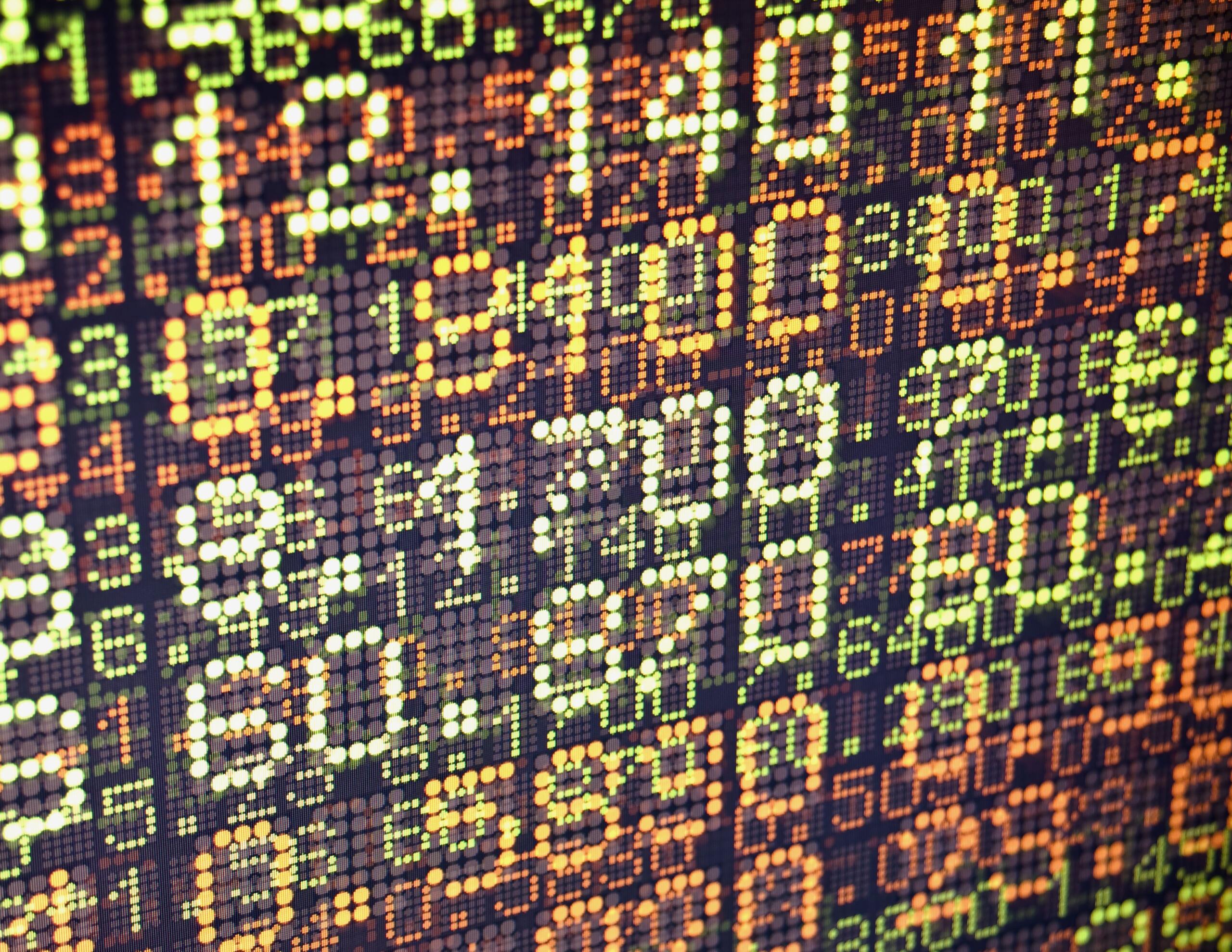 Close-up of a colorful LED dot matrix displaying stock ticker numbers and percentage changes.