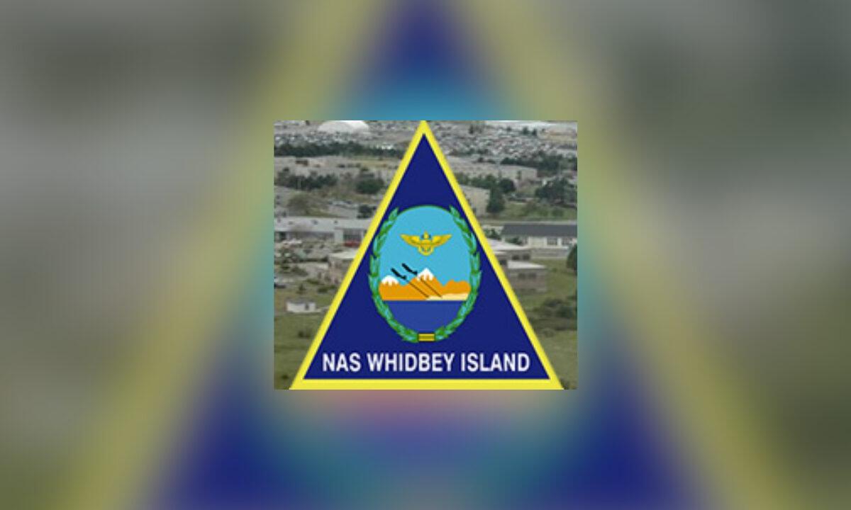NAS Whidbey Island insignia featuring a blue triangle with yellow border and central crest on a blurred background