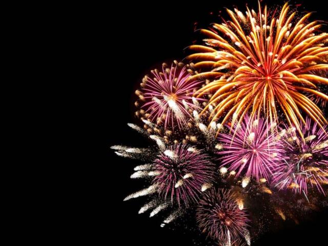 Colorful fireworks exploding in the night sky against a black background.