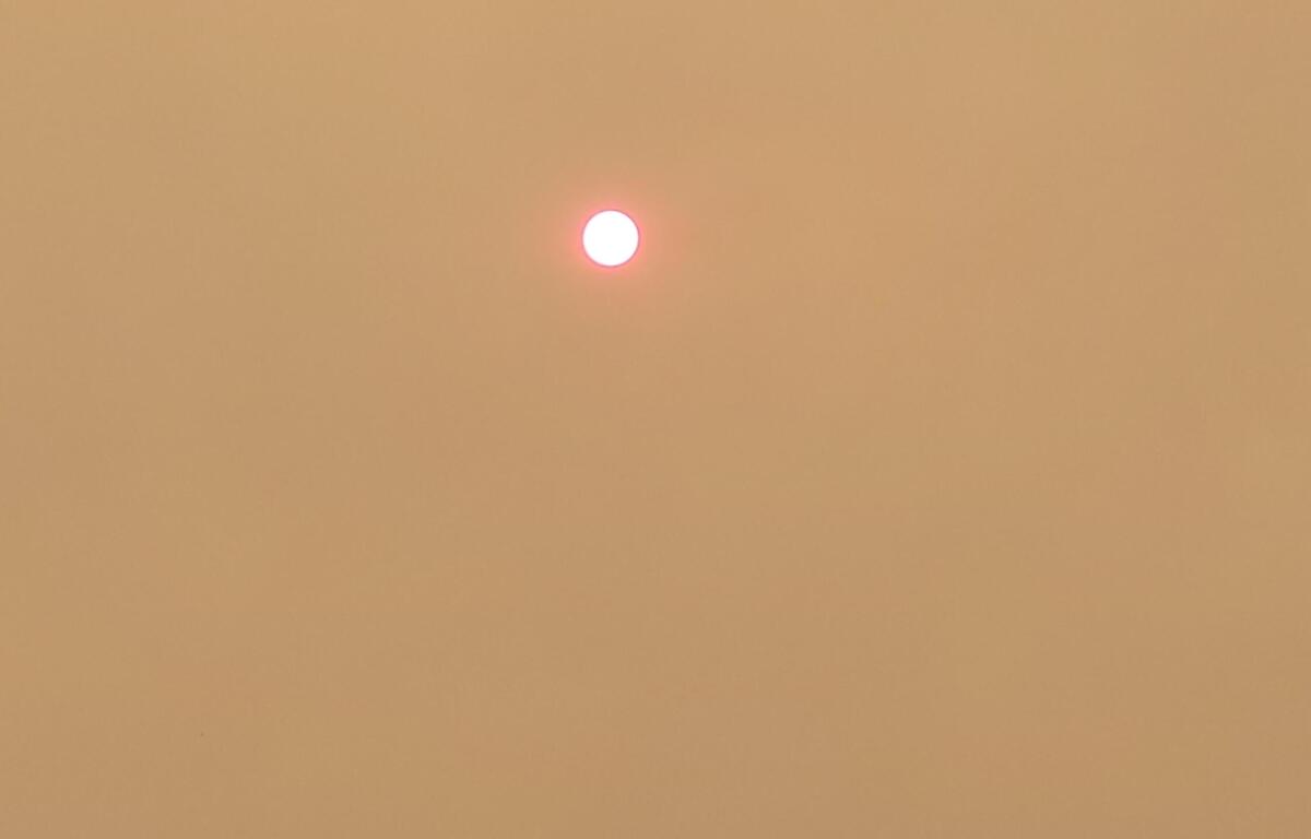 Small bright sun in a hazy orange sky, suggesting sunset or sunrise.