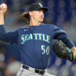 Right-handed pitcher from Seattle in a blue jersey winding up to throw a pitch (number 50).