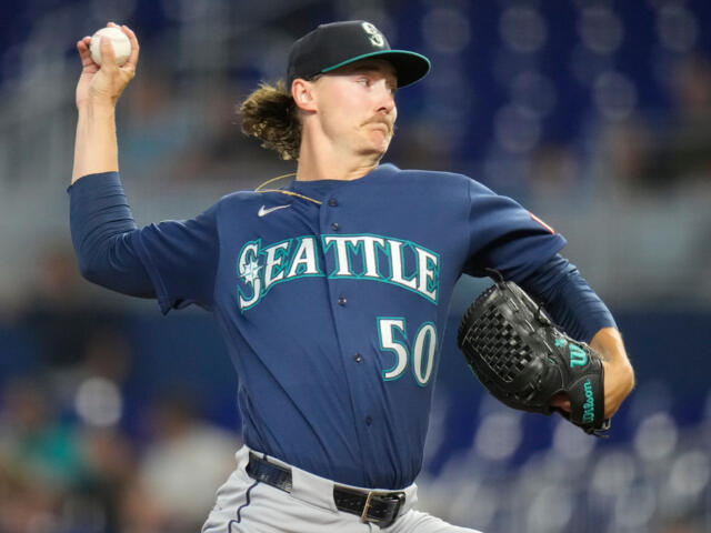 Right-handed pitcher from Seattle in a blue jersey winding up to throw a pitch (number 50).
